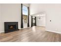 Open living room featuring a fireplace, wood floors, and tall window at 2793 Sandyfalls Way, Las Vegas, NV 89142