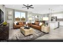 Open-concept living room with modern furnishings, large windows, ceiling fan, and seamless access to the kitchen at 5180 Hisopo St # Lot 24, Las Vegas, NV 89122