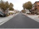 A neighborhood street with mature trees lining the street, sidewalks, and well-maintained homes at 668 Moonlight Stroll St, Henderson, NV 89002