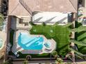 A pristine backyard featuring a pool and hot tub combo, artificial grass, and exterior kitchen area at 8425 Cambrils Ave, Las Vegas, NV 89178
