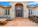 Exterior entrance featuring a covered patio with neutral-toned furniture and a modern front door framed by stone accents at 8509 Iron Mountain Rd, Las Vegas, NV 89143