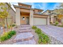 Tan two-story home with well-maintained desert landscaping and a brick driveway and front steps at 12397 Foxtail Run Ave, Las Vegas, NV 89138