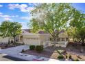 Charming single-story home with a red-tiled roof, mature trees, manicured landscaping, and a two-car garage at 2553 Showcase Dr, Las Vegas, NV 89134