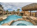 Backyard pool area featuring rock waterfall, slide, spa and covered Tiki Hut at 3892 Pasilla Ave, Las Vegas, NV 89118