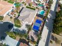 Stunning aerial view of a property featuring a pool, lush landscaping, and a blue and grey sports court at 6214 Ebony Legends Ave, Las Vegas, NV 89131