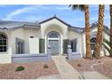 A home's front entrance features unique glass block sidelights, a gray front door, and desert landscaping at 8112 Golfers Oasis Dr, Las Vegas, NV 89149