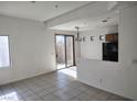 Bright living room with tile flooring, sliding glass doors to backyard, and view into kitchen at 8301 Strawberry Spring St, Las Vegas, NV 89143