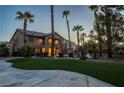 Spacious backyard featuring a covered patio, seating, lush lawn and mature palm trees at 9012 Alpine Peaks Ave, Las Vegas, NV 89147