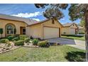 Tan house with a well-maintained lawn, mature landscaping, and a large garage at , Las Vegas, NV 89130