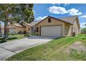 A tan house with a large garage, a well-maintained lawn, and mature landscaping at , Las Vegas, NV 89130