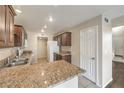 Well-lit kitchen features granite countertops, stainless steel sink, and dark wood cabinets at 10199 Rising Tree St, Las Vegas, NV 89183
