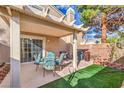 Relaxing covered patio with dining set, synthetic grass and access to the home's interior at 10199 Rising Tree St, Las Vegas, NV 89183