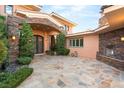 Elegant front entrance featuring stone accents, an outdoor fireplace, manicured landscaping, and custom iron doors at 23 Quiet Moon Ln, Las Vegas, NV 89135