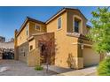 Side view of a tan two-story home featuring manicured landscaping, rock features, and a tile roof at 257 Via Franciosa Dr, Henderson, NV 89011