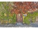 Rustic wooden gate with climbing plants and stone pathway, enhancing the property's curb appeal at 6151 Whispering Sands Dr, Las Vegas, NV 89131