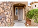 Inviting front entrance with a decorative security door, stone wall detail, and potted plants at 9869 White Lilac St, Las Vegas, NV 89178