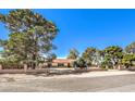 Inviting single-story residence with lush, mature trees and a brick-lined fence offering a serene atmosphere at 10615 Rancho Destino Rd, Las Vegas, NV 89183