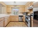 Well-lit kitchen featuring stainless steel appliances, light wood cabinets and tiled floor at 1851 Hillpointe Rd # 2412, Henderson, NV 89074