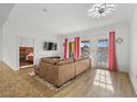 Living room area featuring a comfortable brown sofa, TV, and access to the balcony at 30 Strada Di Villaggio # 409, Henderson, NV 89011