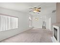 Open living room featuring neutral carpet, ceiling fan, and a fireplace at 3643 Spring Willow Ct, Las Vegas, NV 89147