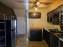 View of the kitchen with dark cabinets, a refrigerator, open shelving, and access to a staircase at 3967 Visby Ln, Las Vegas, NV 89119