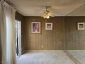 Vacant living room features neutral carpet, ceiling fan, and wall mirror, sliding door and bland vertical wall paper at 3967 Visby Ln, Las Vegas, NV 89119
