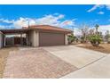 Charming single story home featuring a brown two-car garage, a covered carport and desert landscaping at 436 Concord Way, Henderson, NV 89015