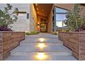 Inviting front entrance featuring illuminated steps, modern landscaping, and an oversized glass door at 6690 Interstellar St, Las Vegas, NV 89135