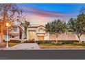 Charming home with a tile roof, lush landscaping, and a well-maintained front yard under a colorful sky at 8390 Carmel Ridge Ct, Las Vegas, NV 89113