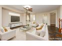 Bright living room featuring modern white furniture, a large TV, and a stylish ceiling fan at 9211 Placer Bullion Ave, Las Vegas, NV 89178