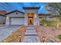 Exterior shot showing a home's entrance with desert landscaping, a paver walkway, and accent lighting at 101 Mirage View Dr, Henderson, NV 89011