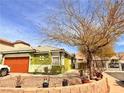 Landscaped front yard with green and white exterior, and orange garage door at 1080 Laguna Park Ct, Las Vegas, NV 89110