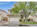 Charming two-story home featuring a well-manicured lawn, mature tree, and attached two-car garage, presenting lovely curb appeal at 2033 Shining Feather Ln, Las Vegas, NV 89134