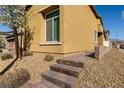 Attractive yellow stucco exterior with steps to the front porch, and desert landscaping and a white-framed window at 332 Coldwell Station Rd, North Las Vegas, NV 89084