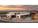 Striking modern home exterior featuring clean lines, neutral colors, ample parking, and desert landscaping against a scenic sunset at 709 Dragon Peak Dr, Henderson, NV 89012