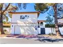 Charming two-story home with a garage, red brick driveway, and well-maintained yard, under a clear sky at 2204 Plaza De La Candela, Las Vegas, NV 89102