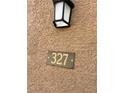 Close-up of the unit number plaque, labeled 327, affixed to a textured tan wall with a porch light above at 2900 Sunridge Heights Pkwy # 327, Henderson, NV 89052