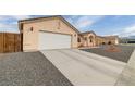 Long driveway leading to a two-car garage of a neutral home, complemented by rock landscaping at 672 Lampshire Ln, Pahrump, NV 89060