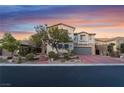 Charming two-story home with a brick driveway, stone accents, and a well-maintained front yard at sunset at 872 Timber Walk Dr, Henderson, NV 89052