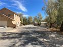 Expansive gravel yard with trees and a detached garage, offering ample space and privacy at 1851 Pinto Ln, Pahrump, NV 89060