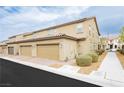 View of the garages of the townhome-style homes with desert landscaping and neutral stucco finish at 2871 Cabrillo Terrace St, Henderson, NV 89044