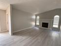 Bright living room with vaulted ceilings, a cozy fireplace, and modern gray floors at 325 Greenfield Ln, Las Vegas, NV 89107