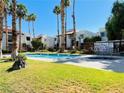Community pool area with lush green lawn and well-maintained landscaping under a clear blue sky at 5117 Eldora Ave # 4, Las Vegas, NV 89146