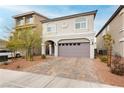 Charming two-story home featuring a brick driveway, gray garage door, and manicured landscaping at 5384 Knitmore Ct, Las Vegas, NV 89139