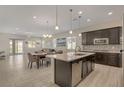 Open-concept kitchen with dark cabinets, a white quartz island, and stainless steel appliances with an adjacent dining area at 5518 Taylor Rose Ave, Las Vegas, NV 89139