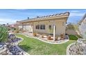 Landscaped backyard featuring a covered patio, well-manicured lawn, and desert-friendly rock features at 6151 Naha Port Ave, Las Vegas, NV 89110