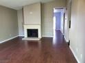 Spacious living room with a cozy fireplace and wood-look floors that extend into the hallway at 7008 Copperleaf Dr, Las Vegas, NV 89128