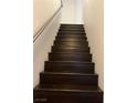 View of a dark wood staircase with a stainless handrail in a neutrally decorated home at 7139 S Durango Dr # 218, Las Vegas, NV 89113