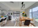 Bright dining area with modern light fixture, wood table and views of the backyard through the sliding glass doors at 2205 Mccoig Ave, Las Vegas, NV 89119
