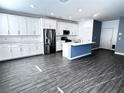 Open kitchen with stainless appliances, island, white cabinets, and hardwood floors at 290 Mount Williamson St, Henderson, NV 89015